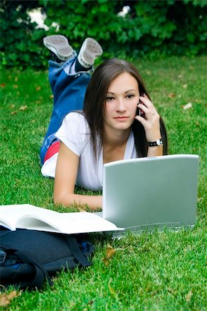 Cute teen girl laying down on the grass studying with her laptop Stock Photo - Budget Royalty-Free & Subscription, Code: 400-05101655