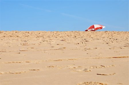 Sand beach close-up with colorful parasol on background over the blue skies Photographie de stock - Aubaine LD & Abonnement, Code: 400-05103026