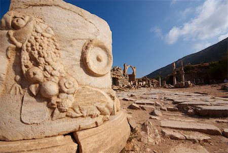 The base of a column in Ephesus, featuring a carved cornucopia. In the background is the Prytaneion. Foto de stock - Royalty-Free Super Valor e Assinatura, Número: 400-05114321