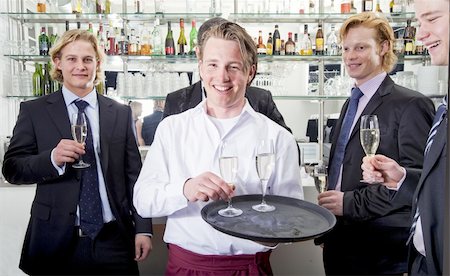 a waiter serving champagne with his customers behind him Stock Photo - Budget Royalty-Free & Subscription, Code: 400-05114510