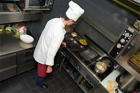 simsearch:400-04114281,k - A shef behind the stove, preparing dinner in a professional kitchen Photographie de stock - Aubaine LD & Abonnement, Code: 400-05114522
