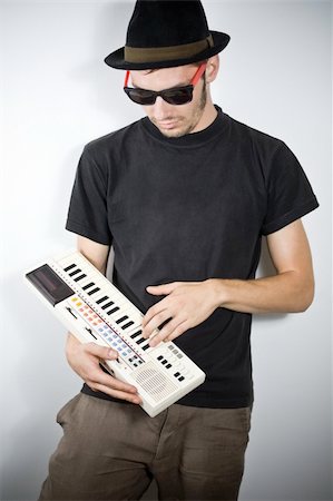 cool guy with hat playing on tiny keyboard Stock Photo - Budget Royalty-Free & Subscription, Code: 400-05115138