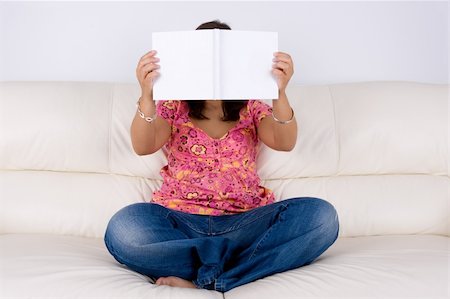 young woman sitting in the sofa reading white book Stockbilder - Microstock & Abonnement, Bildnummer: 400-05115986