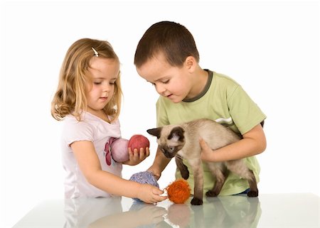 Kids playing with their cat and yarn balls on the table Stock Photo - Budget Royalty-Free & Subscription, Code: 400-05116246