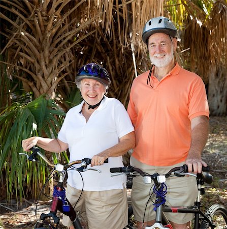 Happy senior couple riding their bikes with helmets on. Foto de stock - Super Valor sin royalties y Suscripción, Código: 400-05116406