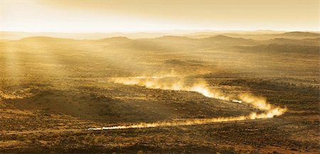 two cars leave plumes of dust as they go through the desert at sunset Stock Photo - Budget Royalty-Free & Subscription, Code: 400-05118703