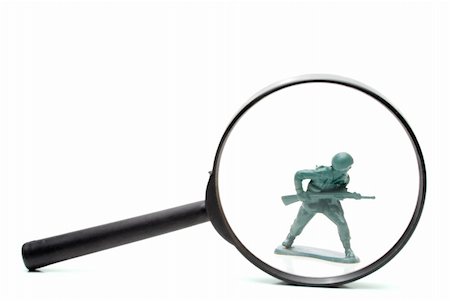 simsearch:640-03258219,k - A toy soldier being investigated under a magnifying glass. Photographie de stock - Aubaine LD & Abonnement, Code: 400-05113425