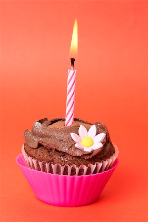 simsearch:400-04815679,k - Miniature chocolate cupcake with icing, decorative flower and birthday candle on red background Foto de stock - Super Valor sin royalties y Suscripción, Código: 400-05125462