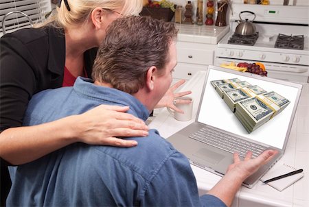 simsearch:400-06857713,k - Couple In Kitchen Using Laptop with Stacks of Money on the Screen. Fotografie stock - Microstock e Abbonamento, Codice: 400-05129324
