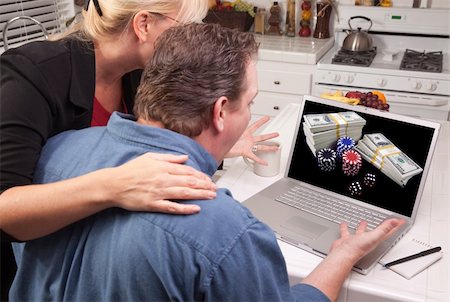 simsearch:400-04053662,k - Couple In Kitchen Using Laptop with Stacks of Money and Poker Chips on the Screen. Stock Photo - Budget Royalty-Free & Subscription, Code: 400-05129326