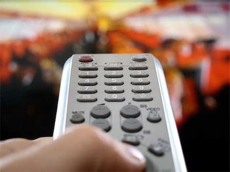 closeup of a hand  holding the remote control in front of the television, shallow DOF, conceptual image of the world under control Stock Photo - Budget Royalty-Free & Subscription, Code: 400-05137598