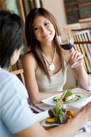 eastwestimaging (artist) - A young woman smiling whilst eating dinner at a restaurant Fotografie stock - Microstock e Abbonamento, Codice: 400-05139803
