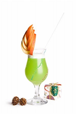 A view of a fancy cocktail glass filled with a delicious green drink and garnished with a sliced apple, a wrapped present and pine cones on a white background. Stock Photo - Budget Royalty-Free & Subscription, Code: 400-05131698