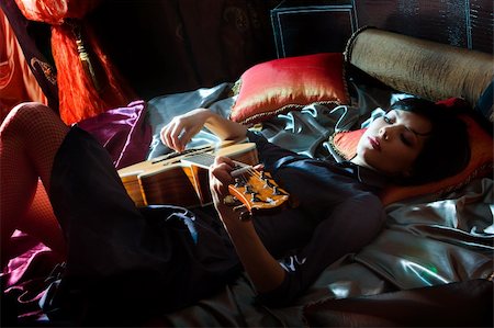 simsearch:400-04348508,k - Young beautiful girl with acoustic guitar lying on the bed Photographie de stock - Aubaine LD & Abonnement, Code: 400-05131915