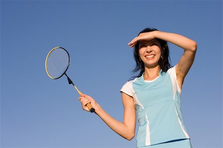 Young woman playing badminton on blue sky background Stock Photo - Budget Royalty-Free & Subscription, Code: 400-05131910
