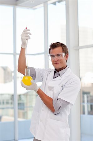 simsearch:400-05218769,k - Scientist examining a test-tube in a laboratory looking at the camera Stock Photo - Budget Royalty-Free & Subscription, Code: 400-05145053