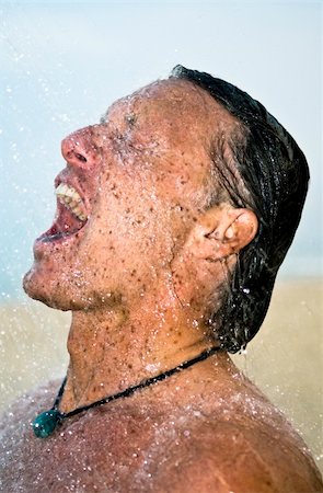 A handsome forties man is taking a wash under a powerful shower at the beach. Foto de stock - Super Valor sin royalties y Suscripción, Código: 400-05149577