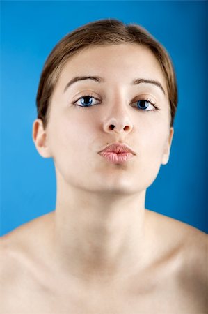 simsearch:400-05192072,k - Close up portrait of a beautiful female model kissing, isolated on a blue background Photographie de stock - Aubaine LD & Abonnement, Code: 400-05149847