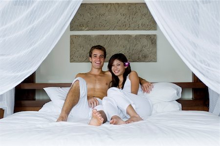 eastwestimaging (artist) - A young couple lying on bed in hotel room Fotografie stock - Microstock e Abbonamento, Codice: 400-05143255