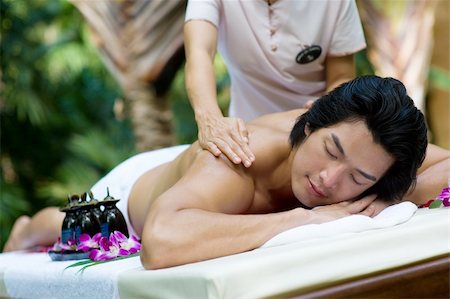 eastwestimaging (artist) - A young man getting a massage outside at a tropical spa Fotografie stock - Microstock e Abbonamento, Codice: 400-05143257