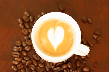piccolo - Top down view of a delicious piccolo latte in a small white cup with a heart shaped coffee art design sitting on a wooden table surrounded by roasted coffee beans. Stock Photo - Budget Royalty-Free & Subscription, Code: 400-05143722