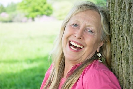 A beautiful older woman in her sixties shows her wonderful smile as she leans against a tree during a day out in the countryside. Foto de stock - Super Valor sin royalties y Suscripción, Código: 400-05152033