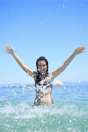 Happy young woman in sea splashing water Stockbilder - Microstock & Abonnement, Bildnummer: 400-05165013