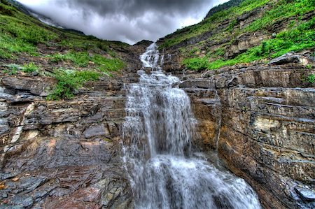 simsearch:400-04904211,k - A cascading waterfall flows down a rocky surface with clouds hugging the mountain top.  Shot in HDR. Fotografie stock - Microstock e Abbonamento, Codice: 400-05166041