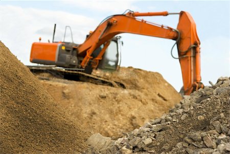 simsearch:400-06171776,k - Orange earth digger on a heap of sand. Focus on the sand in the foreground Fotografie stock - Microstock e Abbonamento, Codice: 400-05167458
