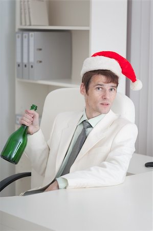The young man in a Christmas cap sits with bottle at a table Stock Photo - Budget Royalty-Free & Subscription, Code: 400-05177907