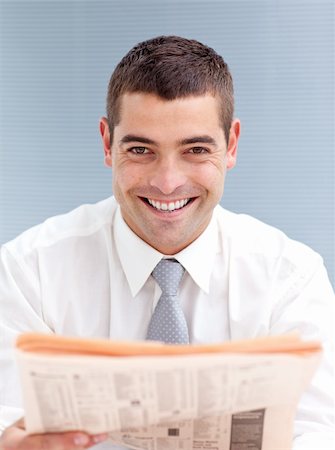 Attractive businessman reading a newspaper smiling at the camera Foto de stock - Super Valor sin royalties y Suscripción, Código: 400-05179429