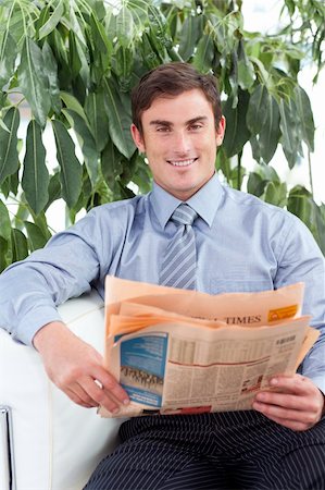 Handsome businessman reading a newspaper smiling at the camera Foto de stock - Super Valor sin royalties y Suscripción, Código: 400-05179441