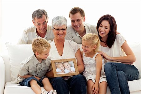 family sitting room sofa grandparents - Happy family holding a portrait of children sitting on sofa at home Stock Photo - Budget Royalty-Free & Subscription, Code: 400-05179493