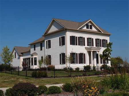 Two story new home built to look like an old historical home complete with the added on look, painted brick and a wrought  iron fence. Stock Photo - Budget Royalty-Free & Subscription, Code: 400-05172312