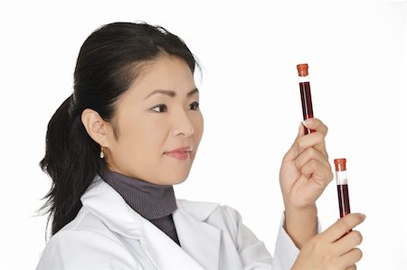Beautiful Asian laboratory technician examining a tube of blood Stock Photo - Budget Royalty-Free & Subscription, Code: 400-05172786