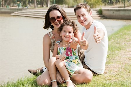family relaxing with kids in the sun - Young family sitting near the lake in the park and giving Thumbs Up Stock Photo - Budget Royalty-Free & Subscription, Code: 400-05180274