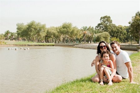 family relaxing with kids in the sun - Young couple embracing and enjoying with young daughter in the park Photographie de stock - Aubaine LD & Abonnement, Code: 400-05180272