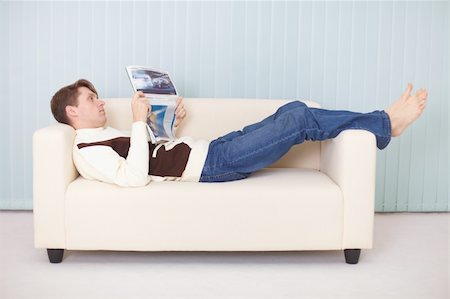 simsearch:400-05195435,k - A young woman lies comfortably on a sofa with a newspaper Stockbilder - Microstock & Abonnement, Bildnummer: 400-05195436