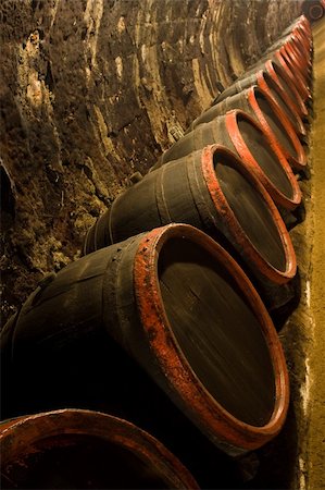 Row of Old wine barrels are stored in winery cellar near aged wall resedes into the distance Stock Photo - Budget Royalty-Free & Subscription, Code: 400-05190445