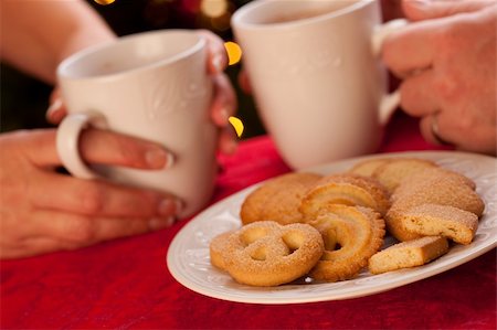 Man and Woman Sharing Hot Chocolate and Cookies in Front of Holiday Lights. Foto de stock - Super Valor sin royalties y Suscripción, Código: 400-05191873