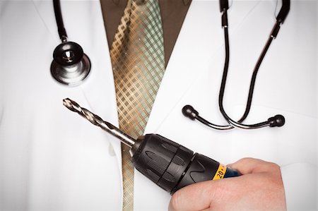 Doctor with Stethoscope Holding A Very Big Drill. Stock Photo - Budget Royalty-Free & Subscription, Code: 400-05192289