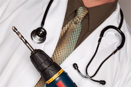 Doctor with Stethoscope Holding A Very Big Drill. Stock Photo - Budget Royalty-Free & Subscription, Code: 400-05192291