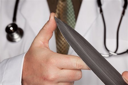 Doctor with Stethoscope Holding A Very Large Knife. Stock Photo - Budget Royalty-Free & Subscription, Code: 400-05192324