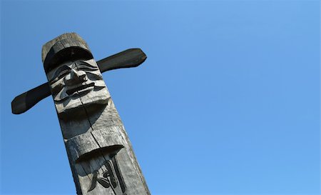 excitator (artist) - Smiling wooden idol on the background of blue sky Foto de stock - Super Valor sin royalties y Suscripción, Código: 400-05193351
