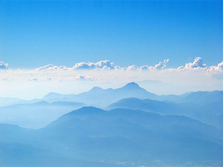 Outline pattern of blue, misty, layered mountains with a line of white clouds and blue sky in the background. Stock Photo - Budget Royalty-Free & Subscription, Code: 400-05193752