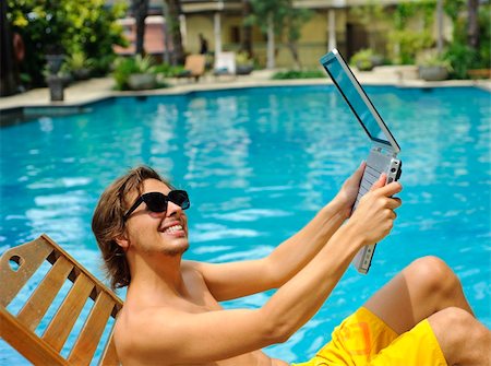 simsearch:400-05209351,k - Man holds laptop up next to the pool Stock Photo - Budget Royalty-Free & Subscription, Code: 400-05209354