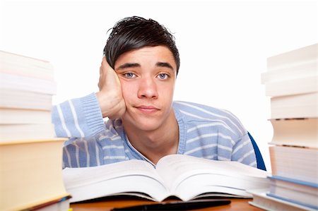 simsearch:400-05678148,k - Young handsome student sitting on a desk between study books and looks frustrated. Isolated on white. Stockbilder - Microstock & Abonnement, Bildnummer: 400-05201068