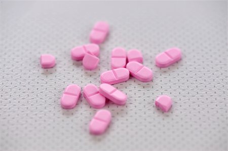 Pink pills, or tablets, scattered on a table-top. Stockbilder - Microstock & Abonnement, Bildnummer: 400-05216838