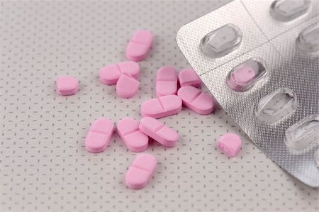 Pink pills, or tablets, alongside an empty blister-pack, scattered on a table top. Stockbilder - Microstock & Abonnement, Bildnummer: 400-05216839
