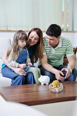 young parrent at home with beautiful child make savings and put coins money in piggy bank Photographie de stock - Aubaine LD & Abonnement, Code: 400-05211276